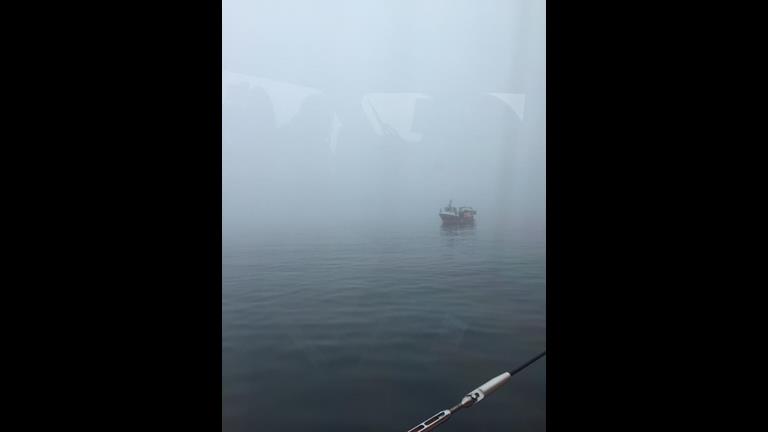 Small red fishing boat through the fog