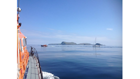 Picture taken from on board the stornoway Lifeboat. Leverburgh Lifeboat towing the yacht with islands in the background.
