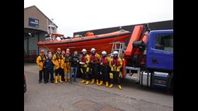 RNLI crew in drysuits standing in front of RNLI Macduff lifeboat B-804 Lydia Macdonald with local footballer Graeme Watt