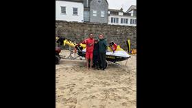 RNLI lifeguards James Symons (L) and Adam Bayfield (R) reunited with Virginia at Porthmeor