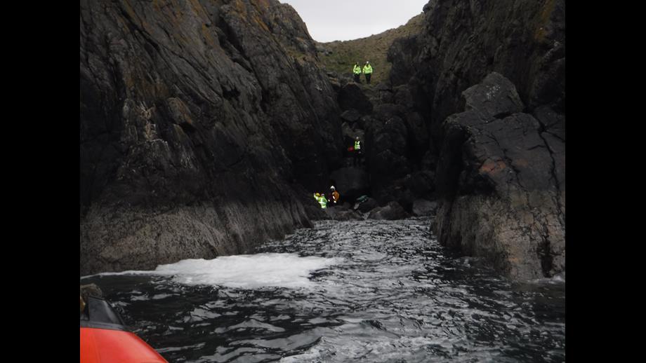 RNLI crew member at the foot of the cliffs with the casualty and member of Scottish Ambulance service