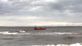 Expanse of water with a lifeboat next to a floating kite flag on the water 