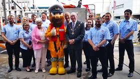 The group are lined up in front along the side of the lifeboat in its carriage. Stormy Stan is in the middle flanked by the rest of the group on either side