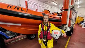 Red Bay crew member, Hazel Imrie, in lifesaving kit, standing in front of the lifeboat