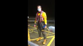 A muddy crew member in full PPE looks muddy and wet as he prepares to hose himself down.