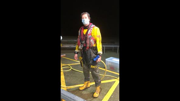 A muddy crew member in full PPE looks muddy and wet as he prepares to hose himself down.