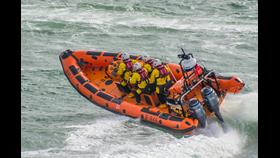 the orange inshore lifeboat speeds through the water with four crew onboard
