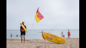 RNLI lifeguard undertaking a patrol between the red and yellow flags