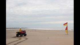 RNLI Lifeguard on all-terrain vehicle (ATV) on the beach