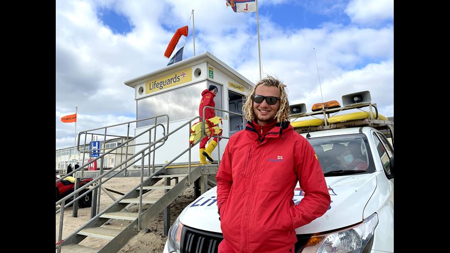 Two RNLI Lifeguards on Camber Sands beach near the lifeguarding hut