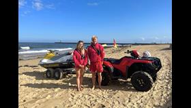 RNLI lifeguards Abby Cass (left) and Chris Trotter (right) in front of an RNLI rescue watercraft
