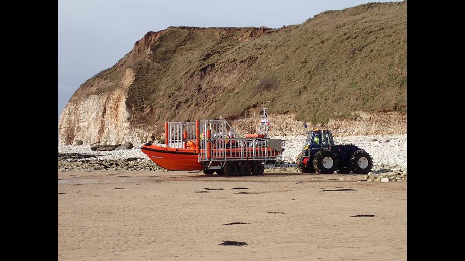 Tractor pulling RNLI B class lifeboat over the beach at South Landing Flamborough