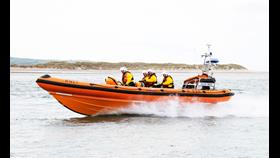 Lifeboat, with several crew members onboard, moving at speed through water 