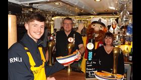 Kyle Park of RNLI Macduff Lifeboat (left) accepts a collecting box containing almost £300 from Derek and Lorraine Toal, proprietors of the Garden Arms Hotel in Gardenstown