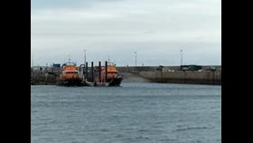 Two, Severn Class lifeboats, either side of a pontoon by a slipway