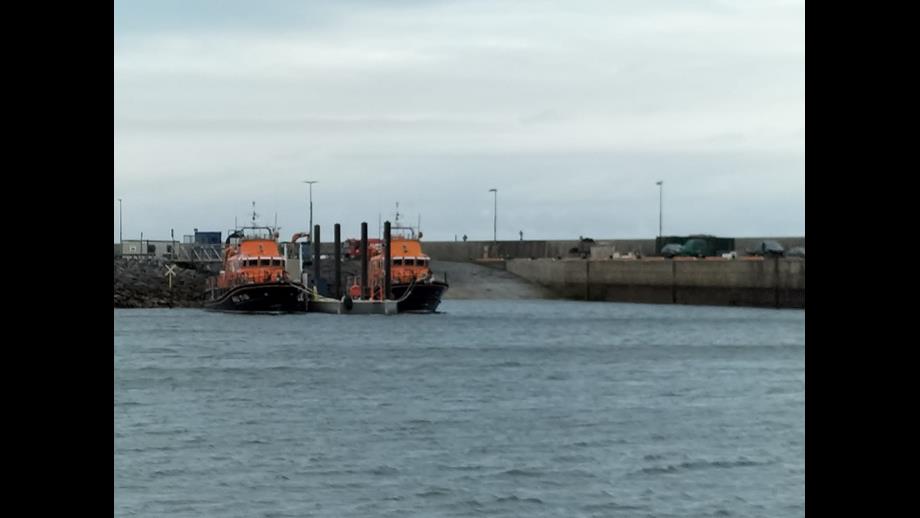 Two, Severn Class lifeboats, either side of a pontoon by a slipway