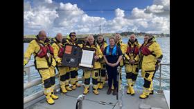 Padstow RNLI volunteers pictured with scroll on boat Padstow Lifeboat