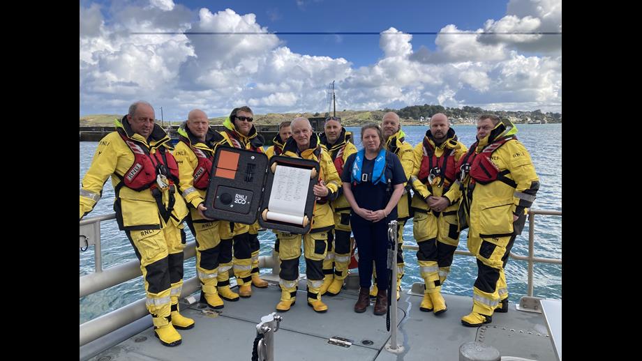 Padstow RNLI volunteers pictured with scroll on boat Padstow Lifeboat