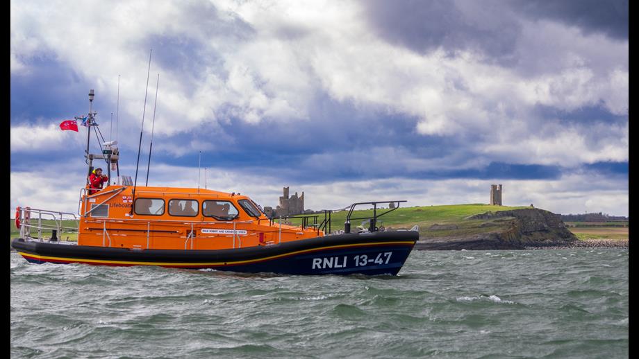 Side shot of Lifeboat 13-47 passing East of Dunstanburgh Castle