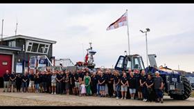 A group of 50 volunteers stand infront the the lifeboat and tractor at Littlestone RNLI