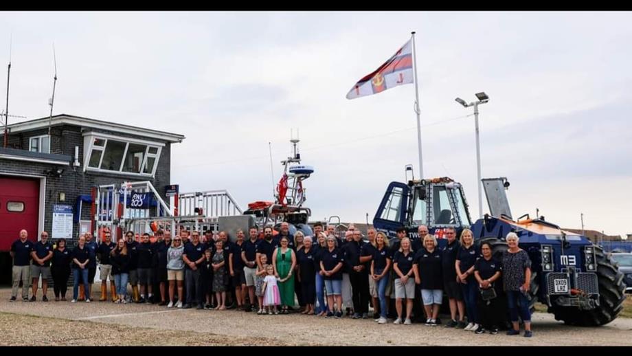A group of 50 volunteers stand infront the the lifeboat and tractor at Littlestone RNLI