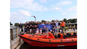Volunteers and their family stand on the pontoon above and behind the lifeboat, which is dressed in RNLI200 bunting for the One Moment One Crew photograph.