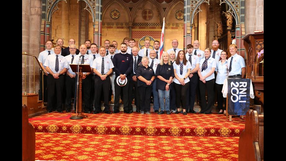Volunteers crew and fundraisers posing for a group photo in front of the altar in St Bees Priory
