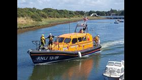 Shannon lifeboat with four crew members on board with small white vessel in foreground