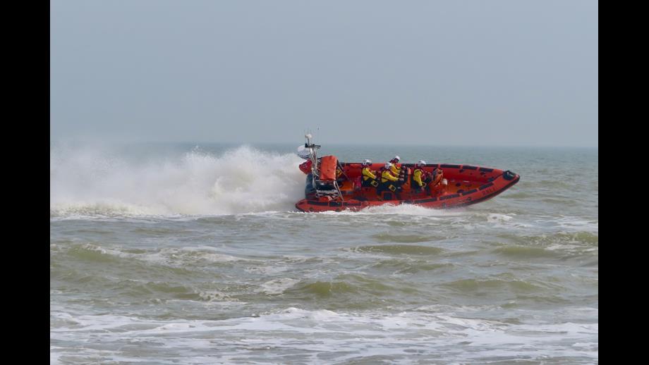 A spectacular picture of the Littlestone RNLI Atlantic 85 lifeboat speeding across the water with surf thrown up behind it