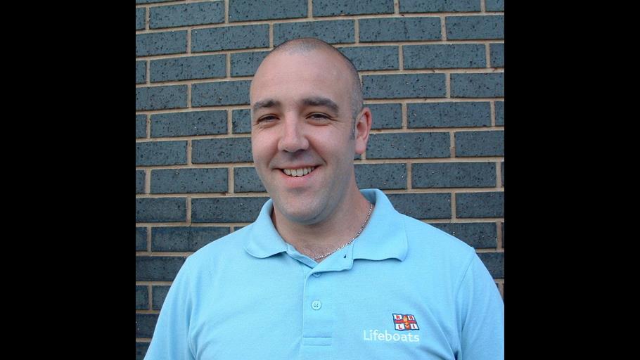 A man in lifeboat sweatshirt smiles at the camera
