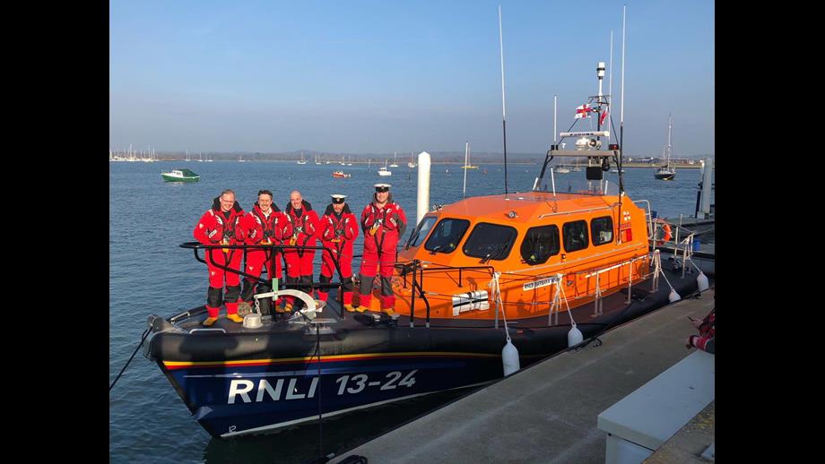 A Shannon class Lifeboat sits alongside a quay with five crew members lined up before leaving on training