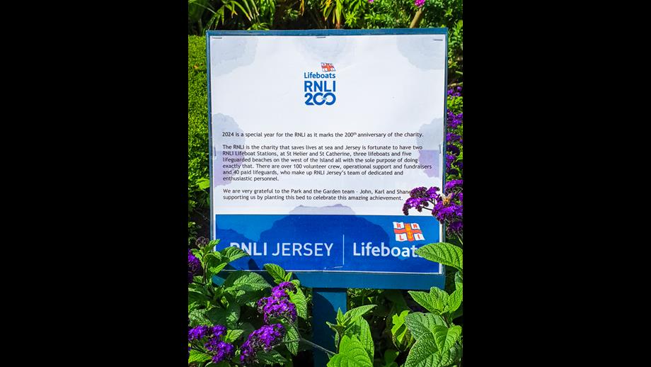 The sign beside the flowerbed dedicates the flowerbed to the RNLI, giving a brief history and ending with the words &quot;We are very grateful to the Park and the Garden team - John, Karl and Shane - for supporting us by planting this bed to celebrate this amazing achievement.&quot;