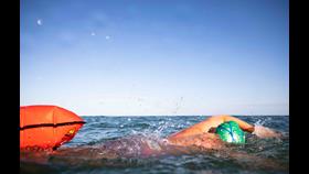 Open-water swimmer with towing float &amp; brightly coloured swim hat