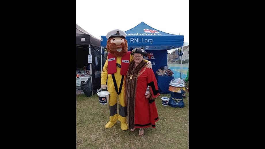 Mascot Stormy Stan wearing yellow with his arm around Mayor.