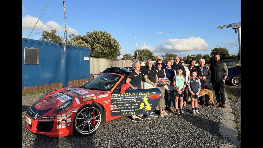 Volunteers from Lough Derg RNLI stand by the Porsche 911 car with the station behind them