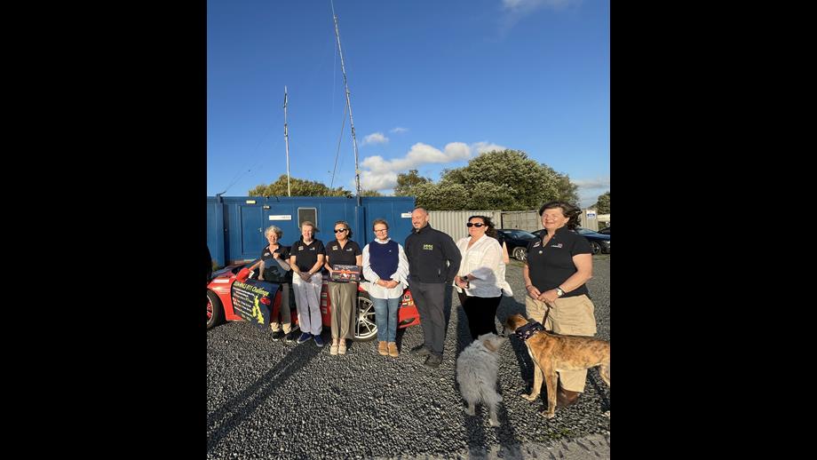 Lough Derg RNLI volunteers being presented with a gift from Michael and Vanessa Nagle, sponsors of this visit of Porsche 911 challenge, in honour of their father - all stand in front of the Porsche, 2 of the volunteers dogs are in the photographs also