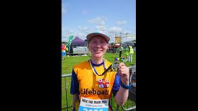 Louise is standing, wearing her Lifeboats T shirt and holding up her medal