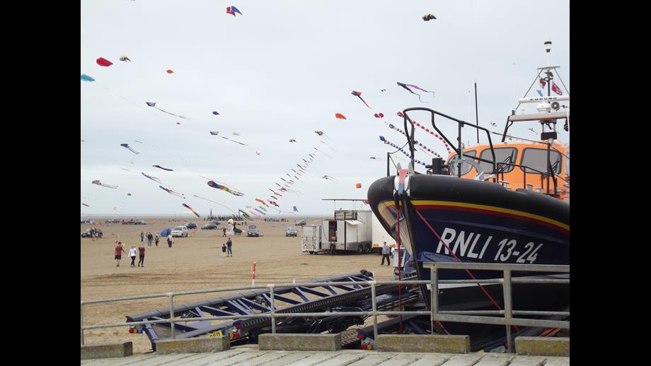 The bow of the Lytham Lifeboat shows to the right with the sky behind full of kites