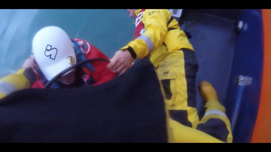 Fishguard lifeboat volunteers assisting a kayaker from their kayak onto the lifeboat.