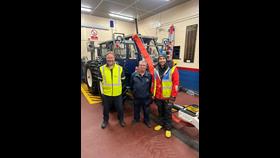Three men standing next to each other whilst standing infront of a tractor