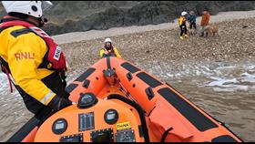 Photo of lifeboat bow on the beach with crew and dog walkers