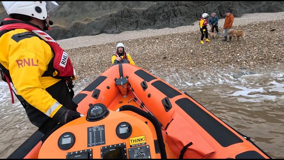 Photo of lifeboat bow on the beach with crew and dog walkers
