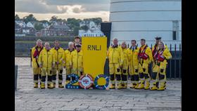 RNLI Lifeboat crew in a team photo standing with 200 Anniversary props