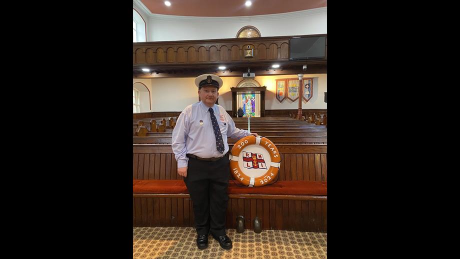 Volunteer crew member standing in church with 200 anniversary prop