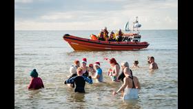 Christmas Dip swimmers with a RNLI lifeboat in the distance