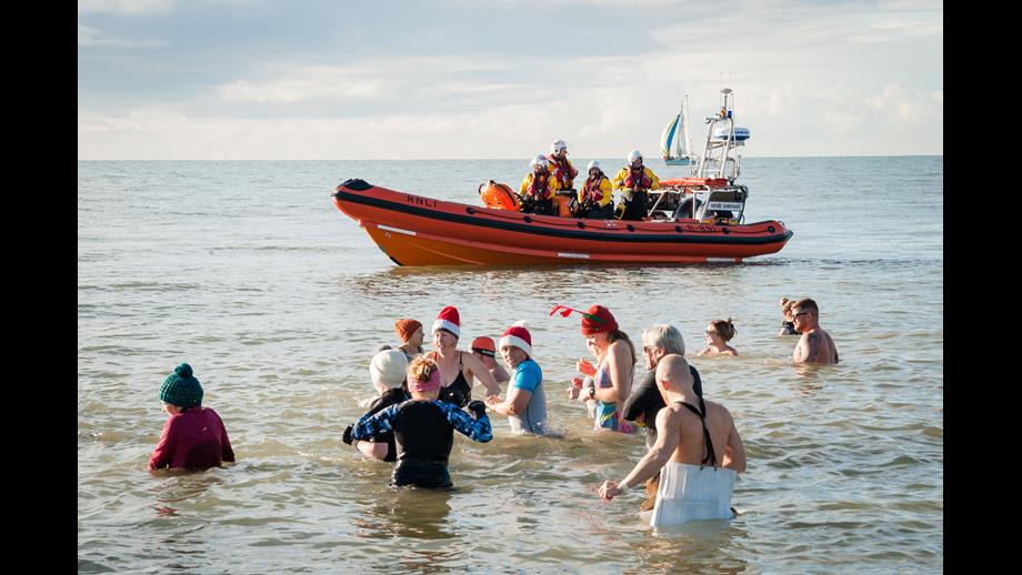 Christmas Dip swimmers with a RNLI lifeboat in the distance