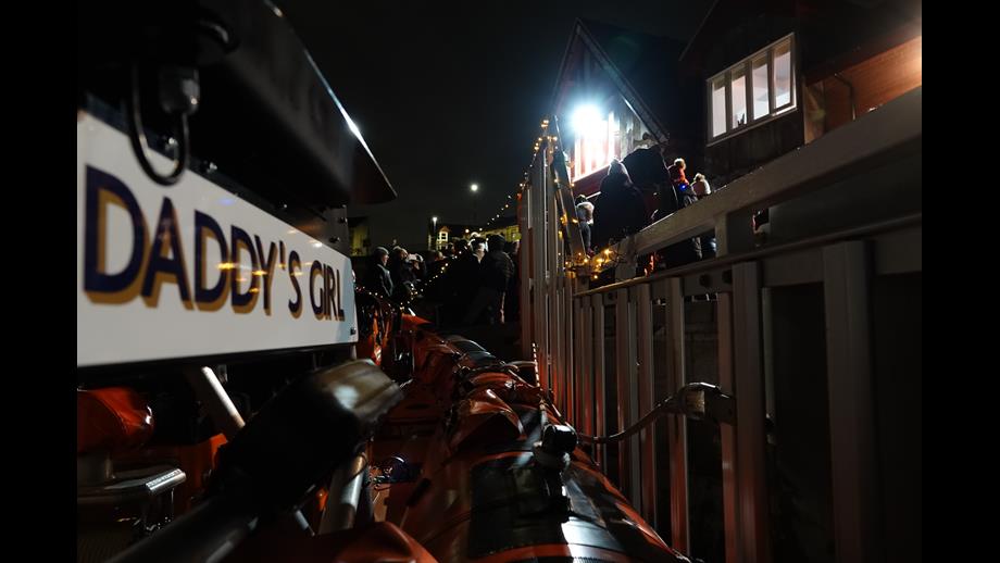 Boat named Daddy's Girl on carriage outside lifeboat station, decorated with Christmas lights