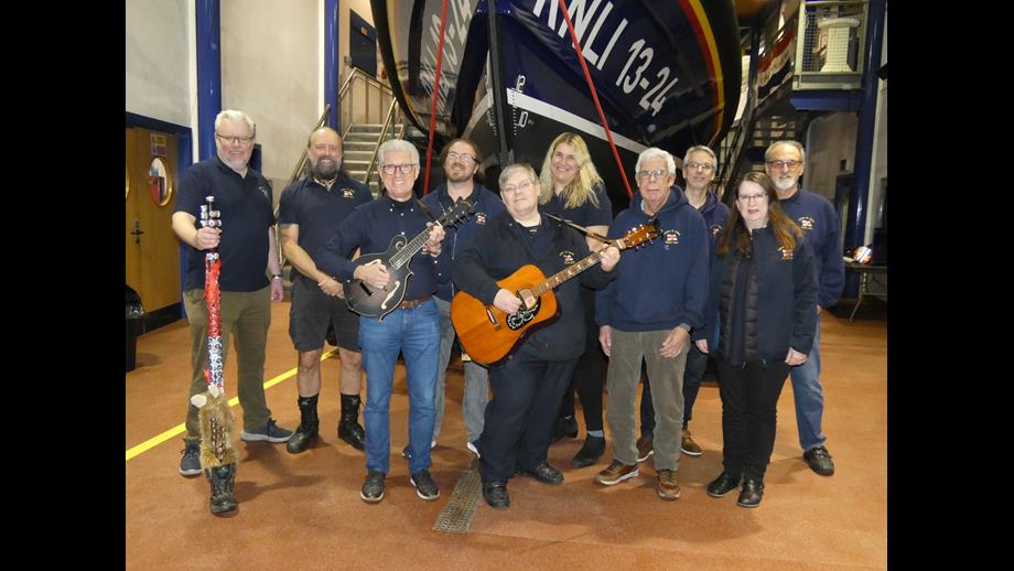 A group of Sea Shanty singers stand in front of a Lifeboat 