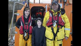 Haydn Sword, age 11, from Eyemouth visits Eyemouth RNLI lifeboat during his Reindeer Run Challenge 2024. Haydn is pictured on the lifeboat with two crew members.