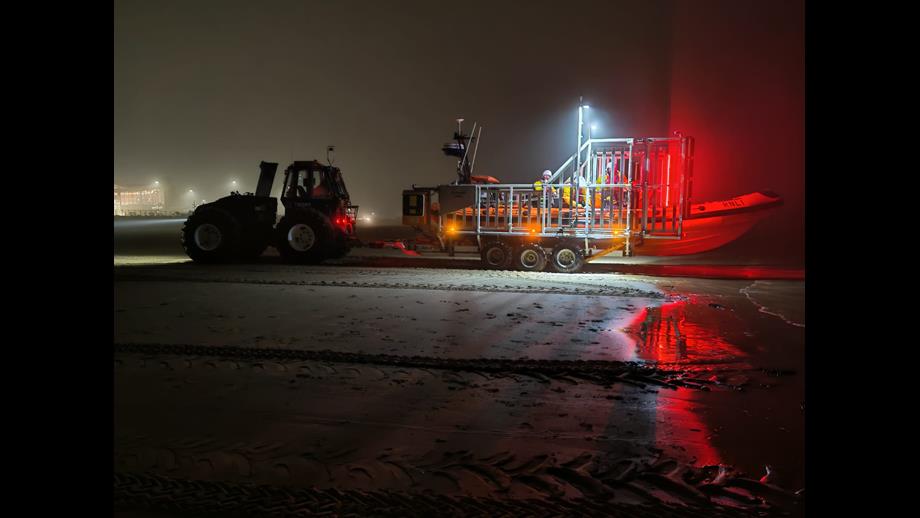 Photo taken from New Brighton beach, of the tractor, carriage and lifeboat, carrying crew, making its way across the beach to the launch site.
